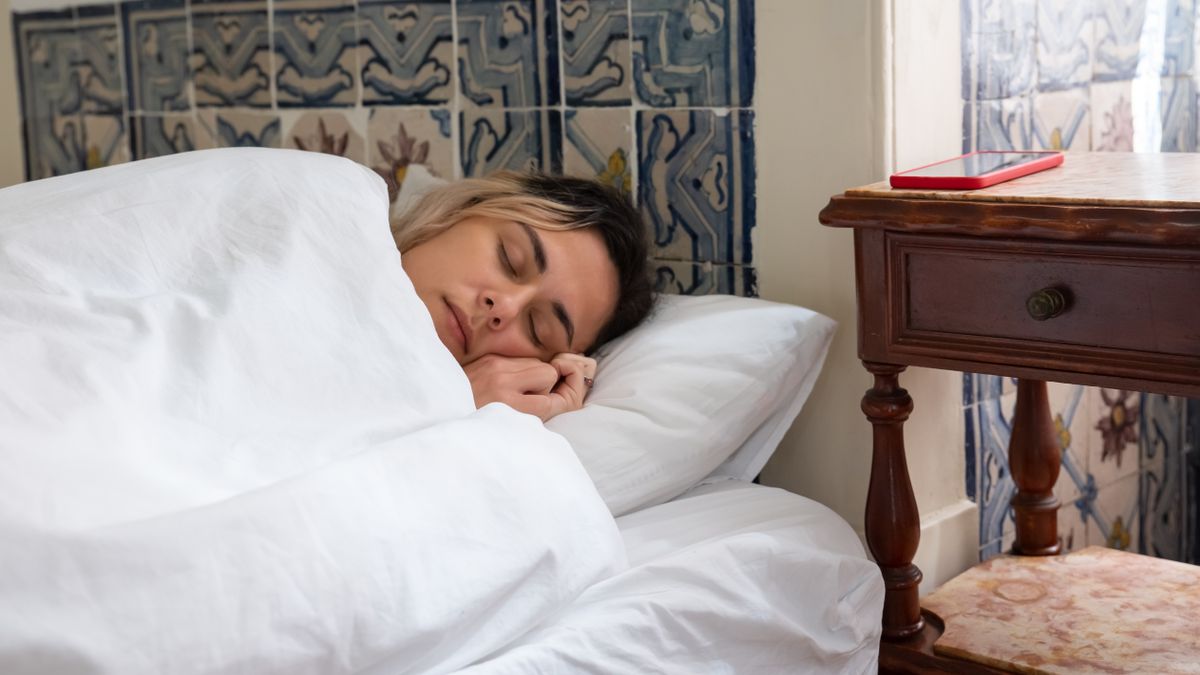 Frau schläft in einem Bett mit weißer Bettwäsche